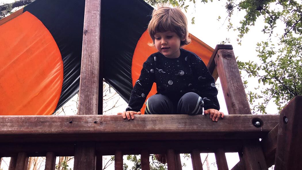 a boy looking off a jungle gym